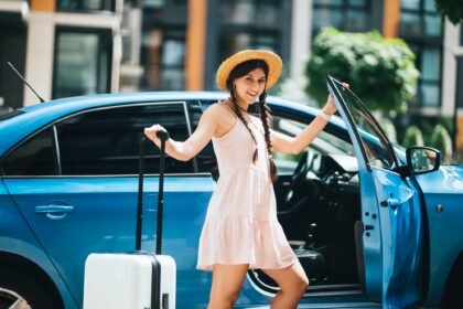 Woman traveling with suitcase near the rental car outdoors